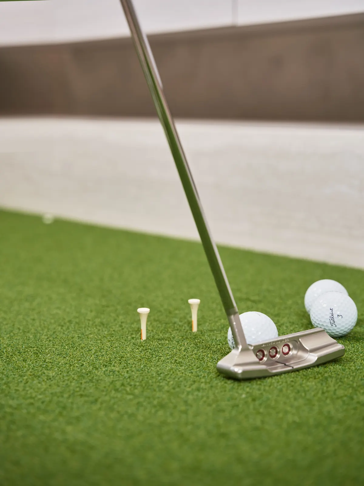 Putter, golf balls, and tees laid out on putting green turf