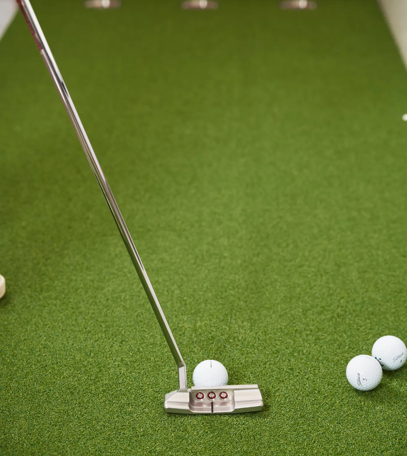 Putter lined up behind a golf ball on a backyard putting green
